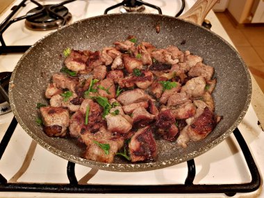 Bir tavada et parçaları kızarmış dilimlenmiş