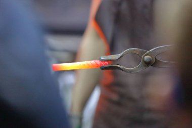 Bir demirci, sahte bir metal işçiliği sergiliyor.