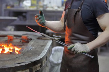 Bir demirci, sahte bir metal işçiliği sergiliyor.