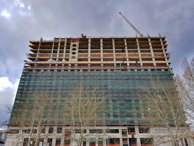 Endüstriyel vinç ve gökyüzünün arka planındaki bir inşaat alanında yüksek binalar.