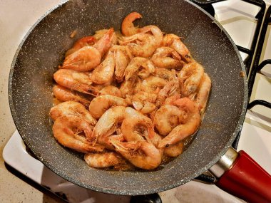 Gaz ocağında tavada yağda kızartılmış dev turuncu karidesler.