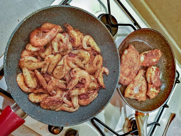Giant orange shrimps fried in oil in a frying pan on a gas stove