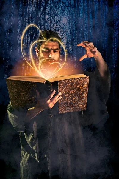 Manliga trollkarl kastar en spell från en magisk bok som halloween ima Stockbild