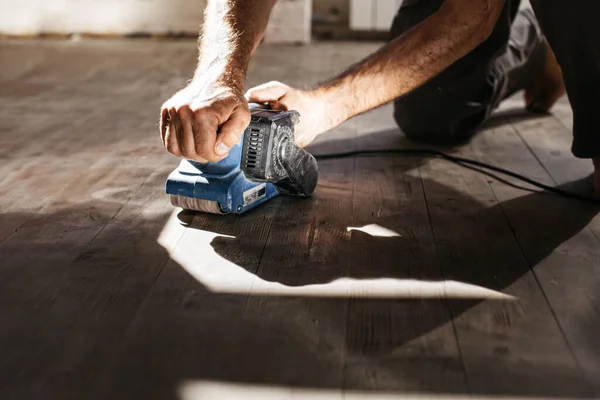 Les hommes font des réparations à la maison. Machine à meuler avec un plancher en bois . — Photo