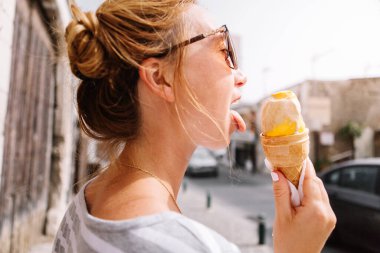 Güneş gözlüklü güzel bir kadın Avrupa sokaklarında yürüyor ve dondurma yiyor..