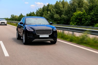 Siyah SUV hızlı yolda hız yapıyor. Otobanda Jaguar E-Pace.