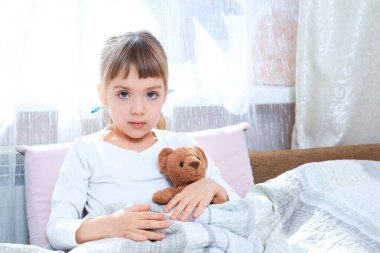 Küçük kız bir oyuncak ayıyla yatakta hasta. Ateş Konsepti. Tedavi eğlencelidir. tıp eğitimi kavramı