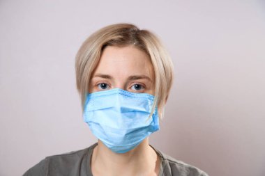 Corona virüsünden korumak için maskeli bir kız. Corona virüsü salgını. Yüz maskesi takan bir kadın, kameraya bakıyor, yaklaş. Grip salgını, toz alerjisi, virüs koruması. Şehir hava kirliliği kavramı