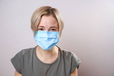 Corona virüsünden korumak için maskeli bir kız. Corona virüsü salgını. Yüz maskesi takan bir kadın, kameraya bakıyor, yaklaş. Grip salgını, toz alerjisi, virüs koruması. Şehir hava kirliliği kavramı