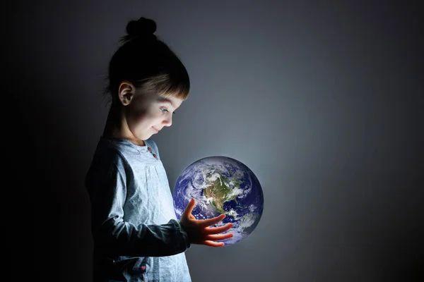 Little cute girl holding a luminous planet Earth in her hands. Earth day. Elements of this image furnished by NASA. — Stock Photo, Image