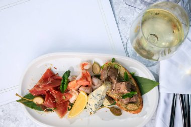 Şarap seti. Jambon, prosciutto, parmesan sosisi, dana eti ve bir bardak beyaz şarap. Metin için yer