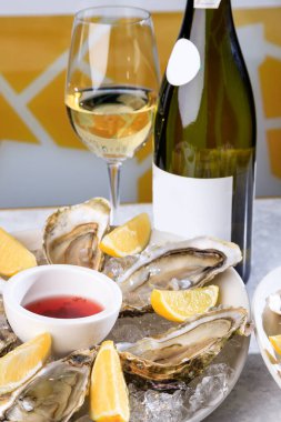 Buz ve limonlu beyaz tabakta taze istiridye. Açık istiridye ve bir bardak beyaz şarap. Lezzetli buzlu istiridye.