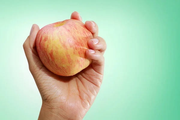 Яблоко в руке изолированы на зеленом фоне . — стоковое фото