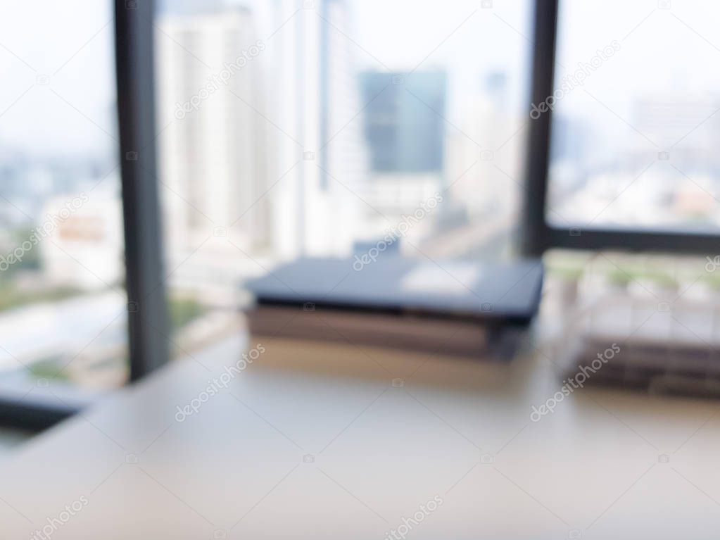 Blurred interior of modern office workplace a workspace design high rise glass window building decorate with document, black, white and wooden furniture. Nice environment can create work productivity.