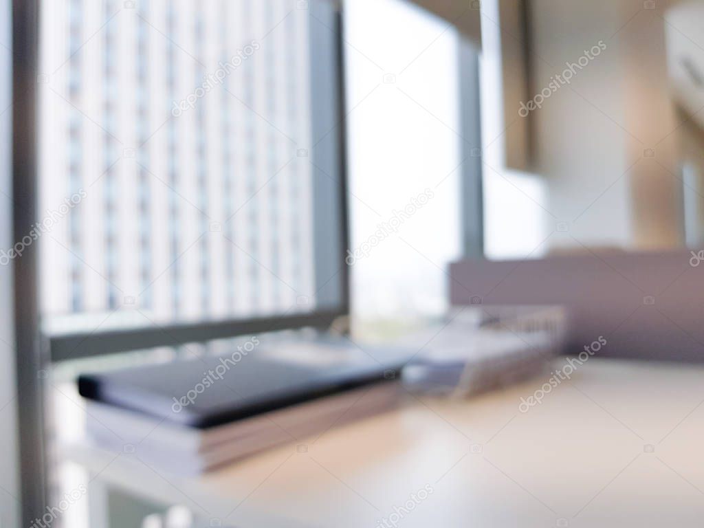 Blurred interior of modern office workplace a workspace design high rise glass window building decorate with document, black, white and wooden furniture. Nice environment can create work productivity.