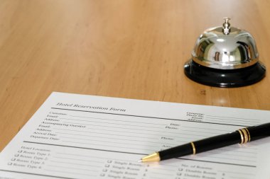 Otel rezervasyonu formu ve danışma masasında lüks bir kalem. Misafirler için bir zil sesiyle birlikte, dikkat. Otel, konukseverlik iş konsepti.
