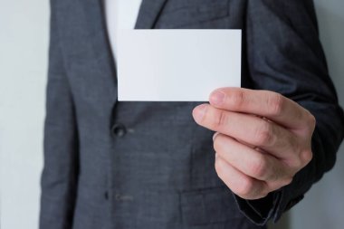 Gri takım elbiseli, beyaz tişörtlü, beyaz kartvizitli erkek işadamları isim ve mesaj atmak için bir şablon hazırlıyorlar. İş konsepti reklamı, iletişim ayrıntıları.