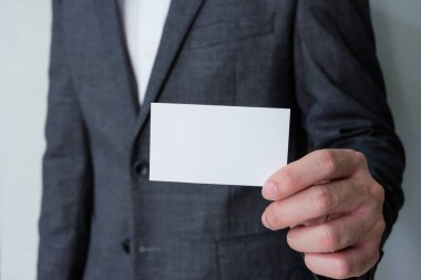 Gri takım elbiseli, beyaz tişörtlü, beyaz kartvizitli erkek işadamları isim ve mesaj atmak için bir şablon hazırlıyorlar. İş konsepti reklamı, iletişim ayrıntıları.