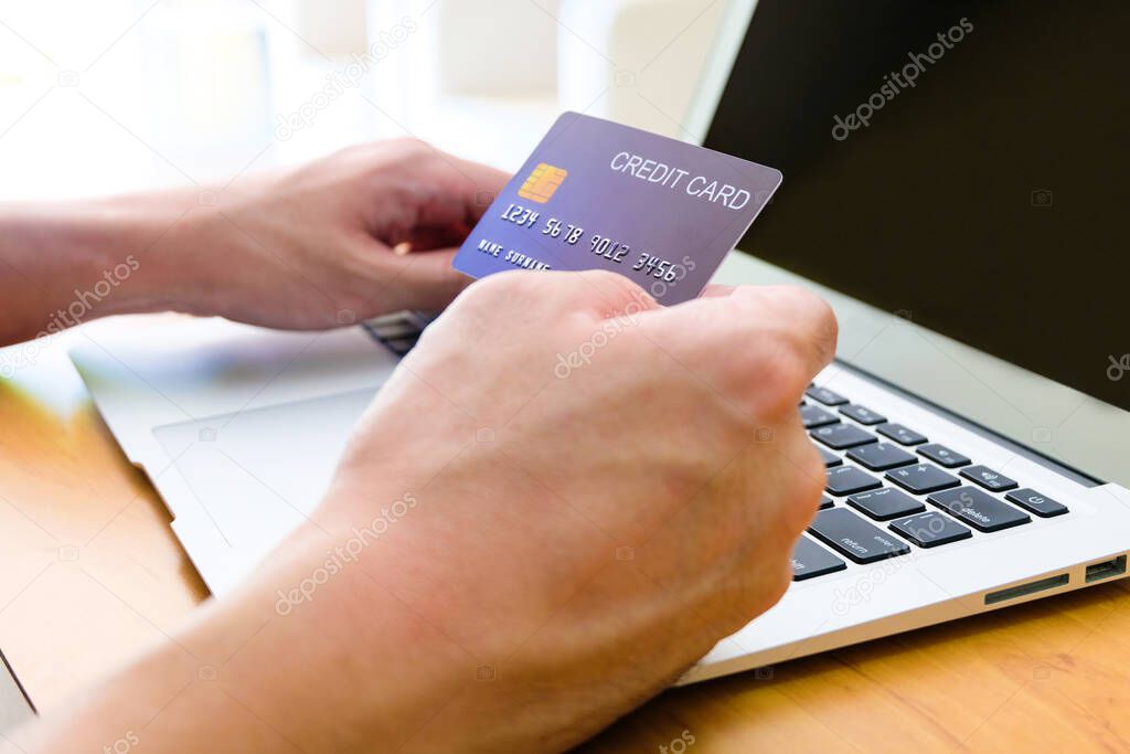 Men hand holding credit card and type payment information on keyboard for order online shopping. Internet technology and Digital market place E-Commerce lifestyle concept, Purchase transaction.