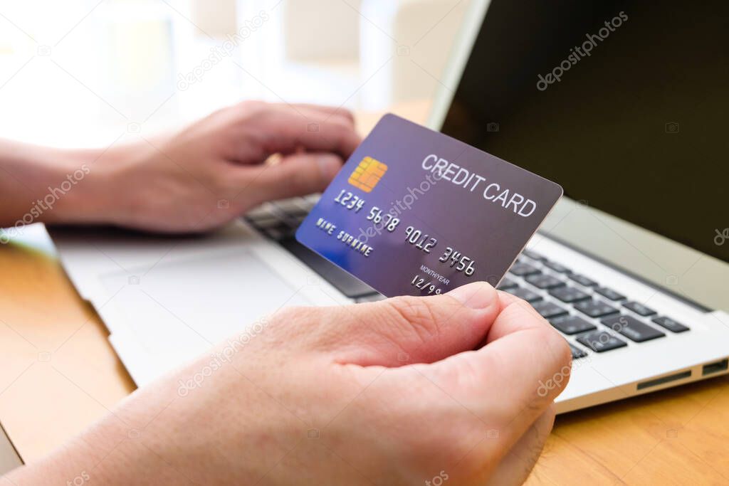 Men hand holding credit card and type payment information on keyboard for order online shopping. Internet technology and Digital market place E-Commerce lifestyle concept, Purchase transaction.