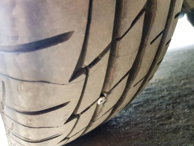 Araba lastiğine çivi saplanmış. Patlak lastiğe yol açabilecek bir kaza. Acil servis gerektiriyor. Yol güvenliği ve bakım kavramı.