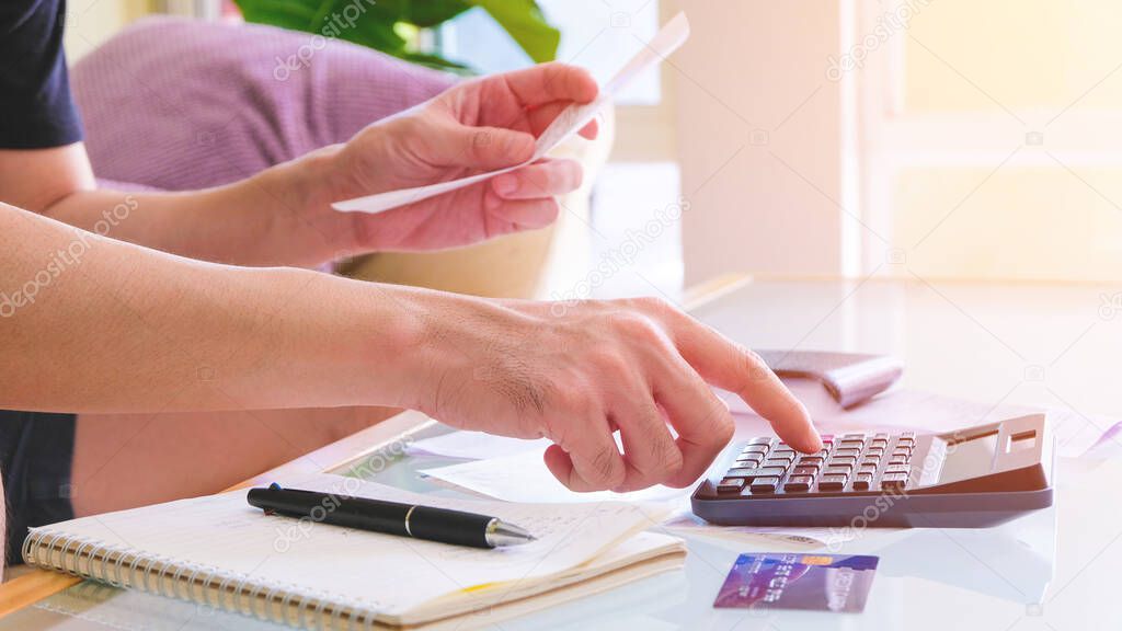 Selective focus of Men using calculator, holding invoice and check his salary for plan personal expense budget. Individual balance sheet for saving and payment control. Financial and economy concept.