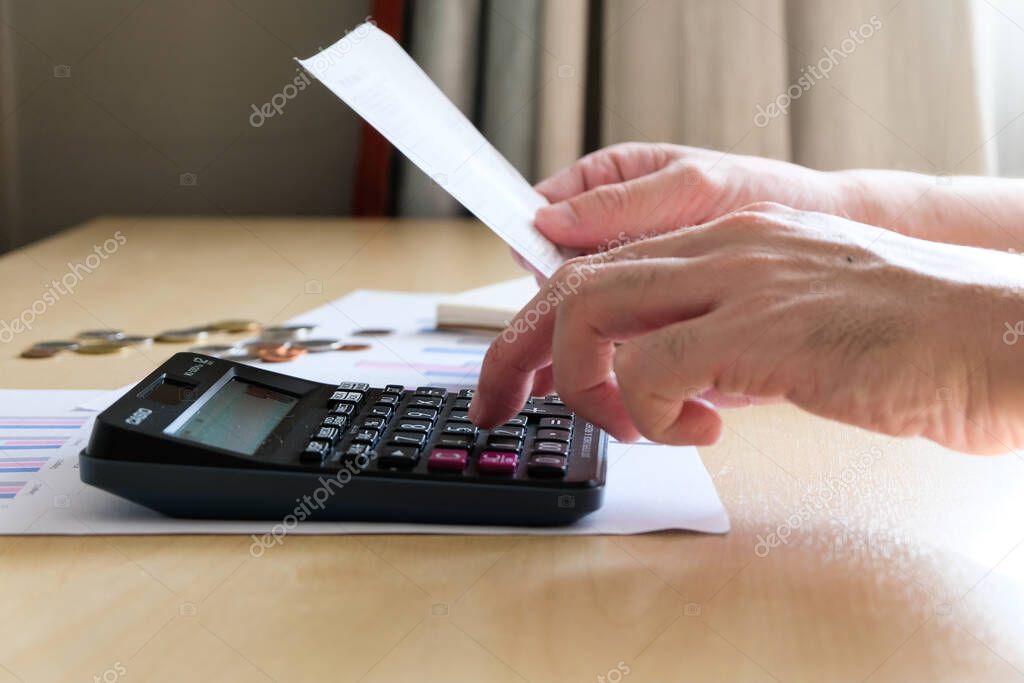 Selective focus of Men using calculator, holding invoice and check his salary for plan personal expense budget. Individual balance sheet for saving and payment control. Financial and economy concept.