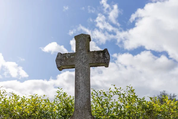 Gris tumba piedra cruz de pie solo en el cementerio, fondo azul cielo —  Fotos de Stock