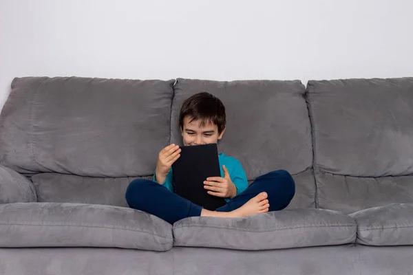 男孩使用平板电脑坐在沙发上，孩子们使用技术，家庭教育，休闲 — 图库照片