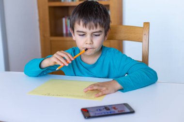 Evde eğitim, küçük çocuk cep telefonuyla ödev yapıyor.