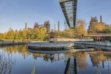 Duisburg - Landschaftspark Duisburg-Meiderich 'teki su rezervuarına bakın. Ağaçlar ve sanayi binaları suya yansıyor, Kuzey Ren Vestfalyası, Almanya, Duisburg, 03.11.2018