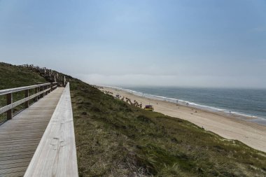 Sylt - Almanya 'nın kuzeyinde Schleswig-Holstein eyâletinde, Wenningstedt' teki Grass Dunes ve Beach 'e doğru tahta kaldırım manzarası