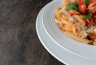 Bolonez soslu makarna, beyaz tabakta beyaz domatesli koyu ahşap arka planda.