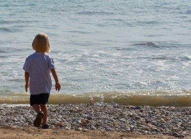 Çocuklar sakin ve mavi kumsala bakıyor.