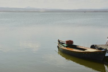 Gün batımında gölde küçük bir tekne, doğanın renkleri.