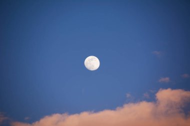 Dolunay mavi gökyüzünde bulutlarla, pamuklu günbatımıyla