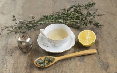 Bir fincan naneli çay ve eski ahşap masada çay süzgeci., 