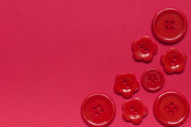 Kırmızı arkaplanda çeşitli kırmızı dikiş düğmeleri.