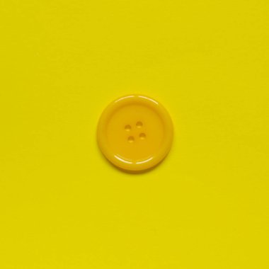 Sarı arkaplanda tek sarı dikiş düğmesi.