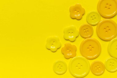 Sarı arkaplanda metin için yeri olan çeşitli sarı dikiş düğmeleri