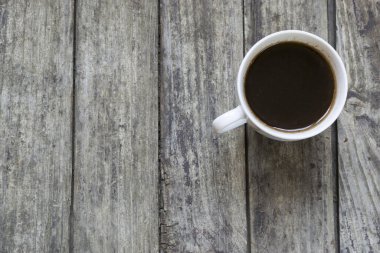 Eski, ahşap masada beyaz bir fincan kahve. Yüksek açı görünümü.