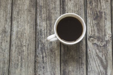Eski, ahşap masada beyaz bir fincan kahve. Yüksek açı görünümü.