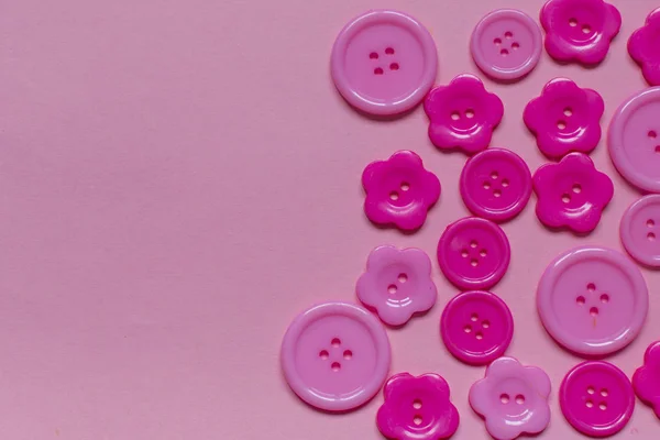 Açık pembe arkaplanda metin için yeri olan çeşitli pembe dikiş düğmeleri