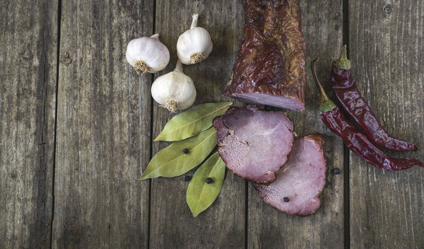 Сушеная свинина с перцем чили, черным перцем, чесноком и лавровыми листьями на старом деревянном столе. Вид под высоким углом, с пространством для текста
.