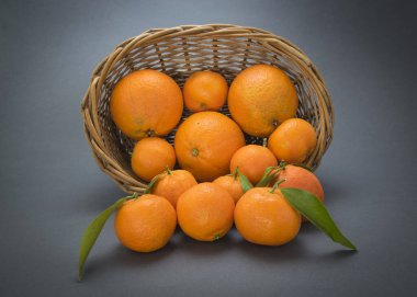 Mavi arka planda sepeti olan portakal ve mandalinalar.