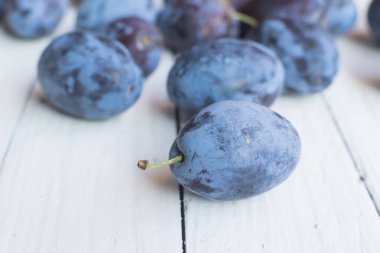 Tahta masadaki diğer eriklerin önünde taze ve lezzetli bir erik.
