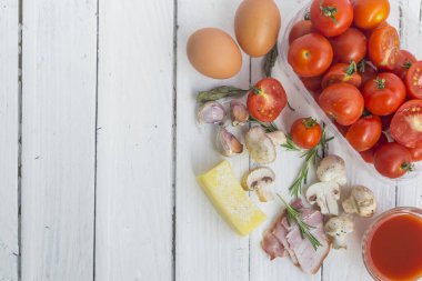 Beyaz arka planda makarna pişirmek için çeşitli malzemeler ve spagetti ile çerçevelenmiş..