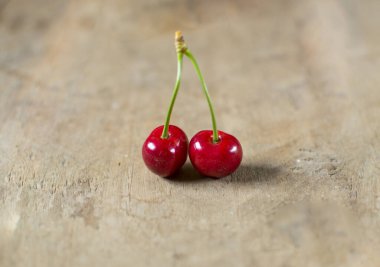 Eski ahşap arka planda iki güzel kırmızı, taze kiraz.