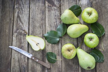 Yeşil armutlar, elmalar ve eski ahşap masa yapraklı bıçak. Yüksek açı görünümü.