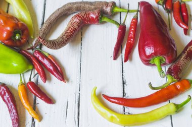 Eski beyaz ahşap masa üzerinde çeşitli renkli ve taze biber (paprika) türleri. Yüksek açı görünümü